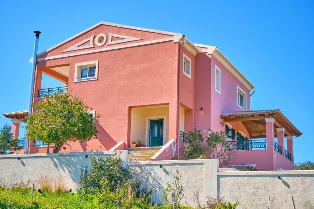 różowy dom z płotem przed nim w obiekcie Villa Melissi Afionas Corfu w mieście Afionas