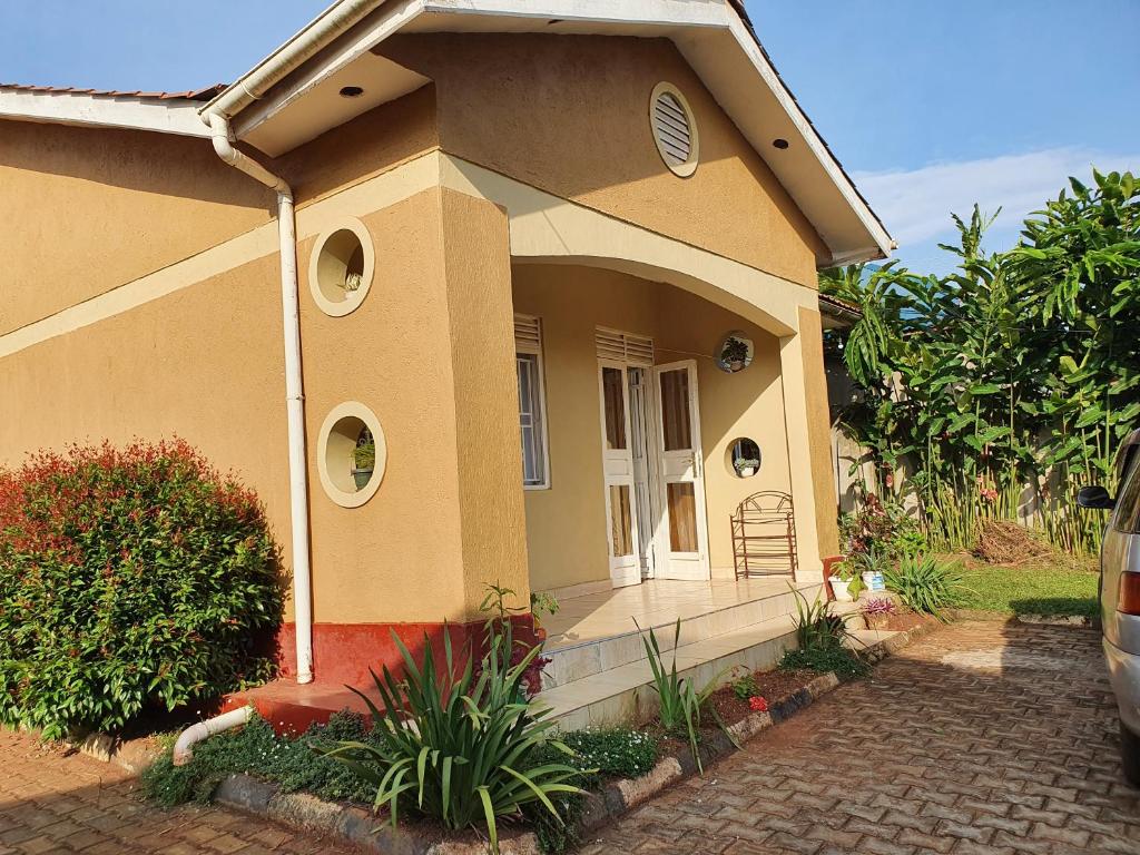 Cette petite maison dispose d'une terrasse couverte et d'une chaise à l'avant. dans l'établissement Dees shared home away from home, à Entebbe