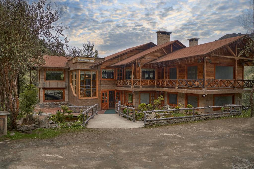 un gran edificio de madera con un porche delante de él en Estancia San Juan en Cuenca