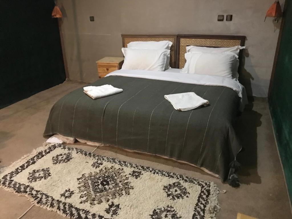 sypialnia z dużym łóżkiem z dwoma ręcznikami w obiekcie Camp birds traquets of SaharaProject house mars six doors w Marakeszu