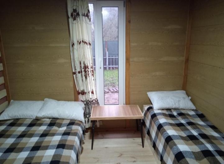 two beds in a room with a table and a window at Дача, будинок,баня in Leplyavo