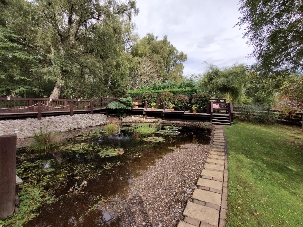 eine Brücke über einen Teich in einem Park in der Unterkunft 7 Burnside House in Kilmorack