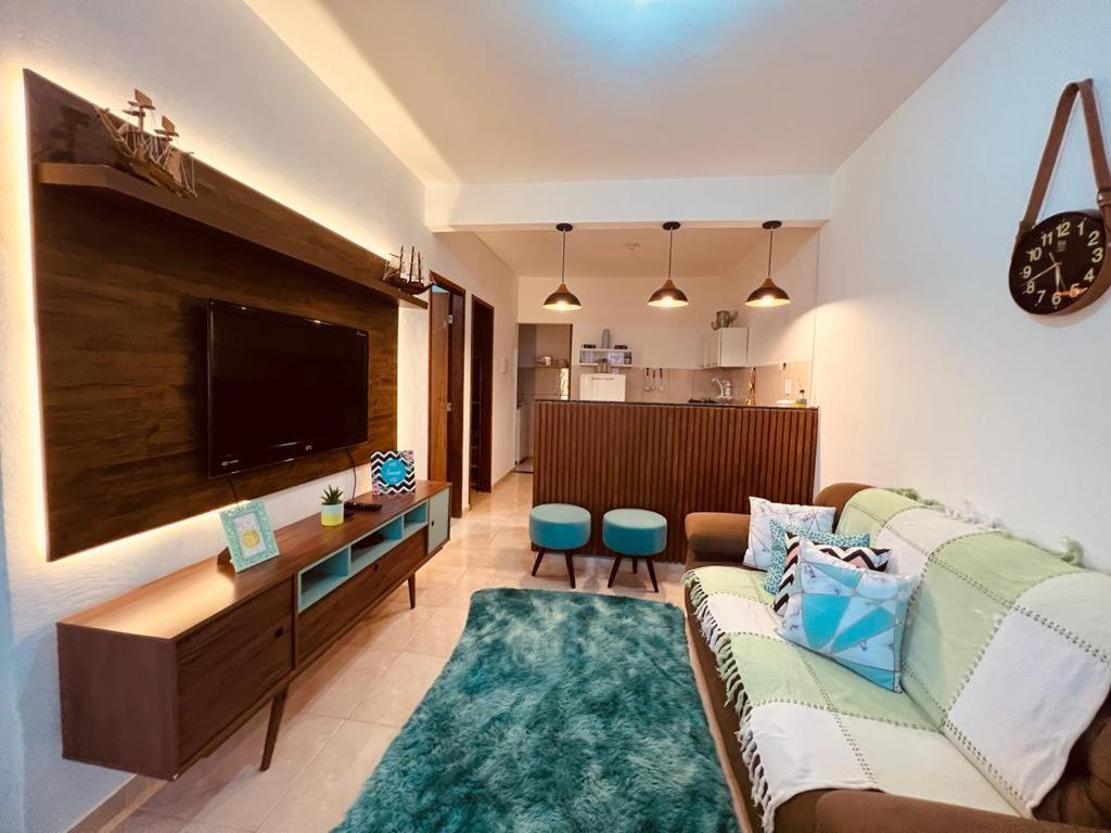 a living room with a couch and a flat screen tv at Apto Aconchego da aldeia 02 ap08 in São Pedro da Aldeia