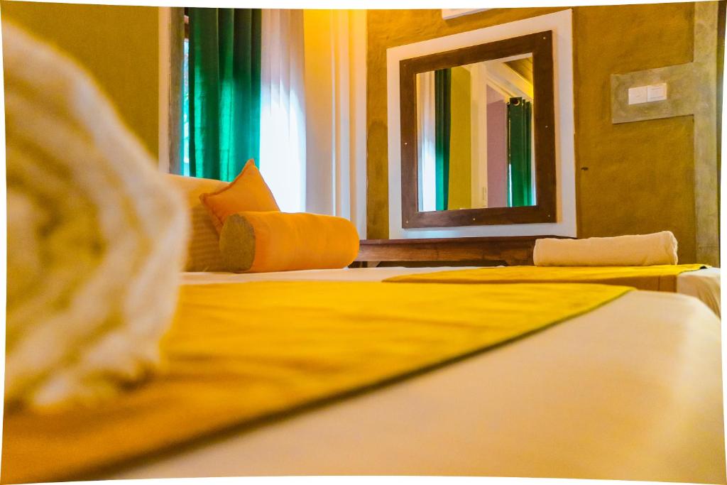 a bedroom with a bed with yellow sheets and a mirror at Summer Will Resort in Moragollagama