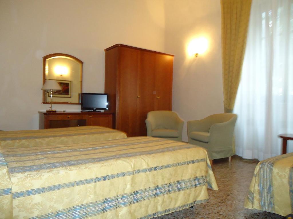 Pokój hotelowy z 2 łóżkami i lustrem w obiekcie Albergo Roma w mieście Casciana Terme