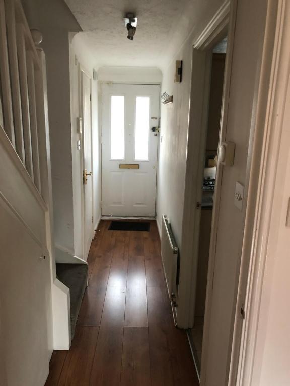 a hallway with a white door and a wooden floor at Lovely 3 Bed Semi Detached house with off street parking located in a quiet Close in London