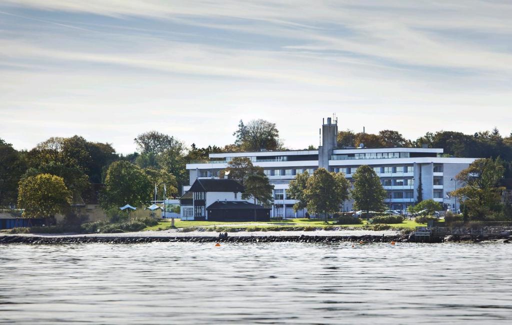 a large white building next to a body of water at Hotel Marina in Vedbæk