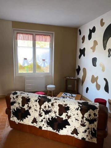 a bedroom with a cow blanket on a bed at Le Moulin du Modon in Couffy