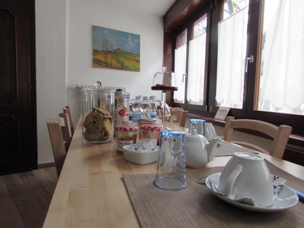 una mesa de comedor con una larga mesa de madera con jarras. en La Casa dei Gatti, en Limone Piemonte