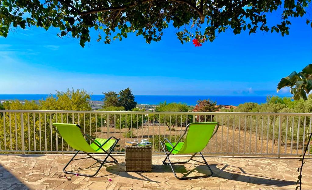 Dos sillas verdes en un patio con el océano en el fondo en Villa BeaBella, en Scicli