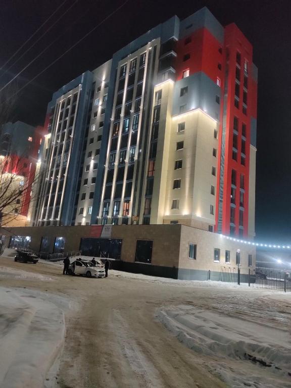 een groot gebouw 's nachts met een auto voor geparkeerd bij ЖК Наурыз парк in Simkent