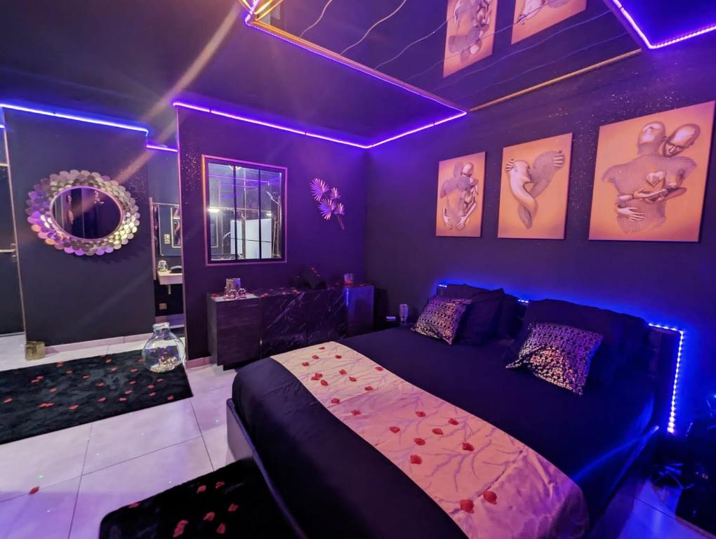 Dormitorio púrpura con cama e iluminación púrpura en Suite Romantique Jacuzzi & Sauna privé Full options TV, en Perpiñán