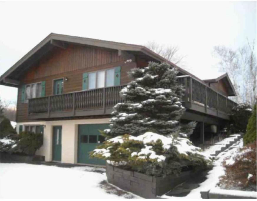 a house with a pine tree in the snow at Mountain view apartment, 5mins to Ski Area! in Windham