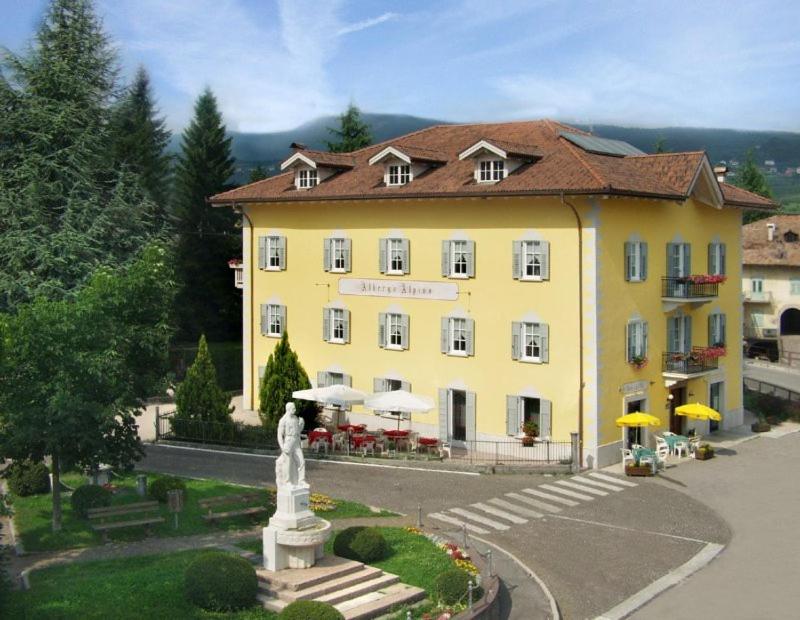 un bâtiment jaune avec une statue devant lui dans l'établissement Locanda Alpina, à Brez