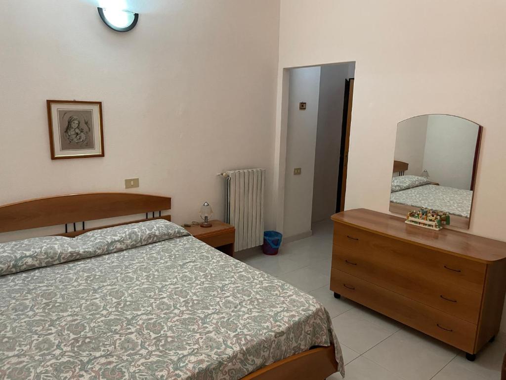 a bedroom with a bed and a dresser and a mirror at Villa Capozza Maria Greca in Le Castella