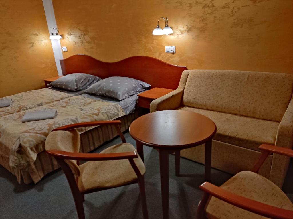 ein Hotelzimmer mit einem Bett, einem Sofa und einem Tisch in der Unterkunft Agroturystyka Kameralna93 in Ochaby
