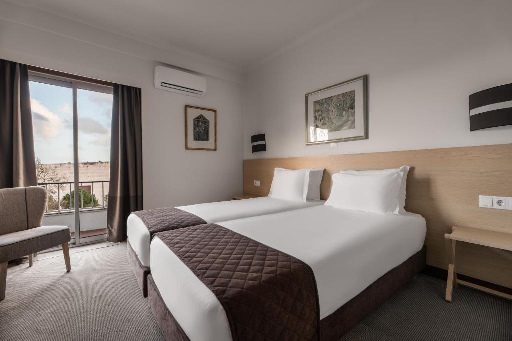 pokój hotelowy z dużym łóżkiem i oknem w obiekcie Crisol Tres Pastorinhos w Fatimie