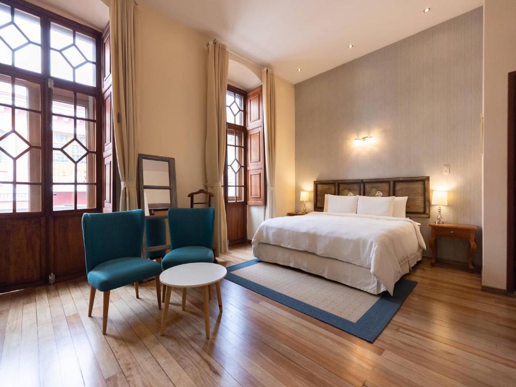 um quarto com uma cama, 2 cadeiras e uma mesa em Casa El Edén em Quito