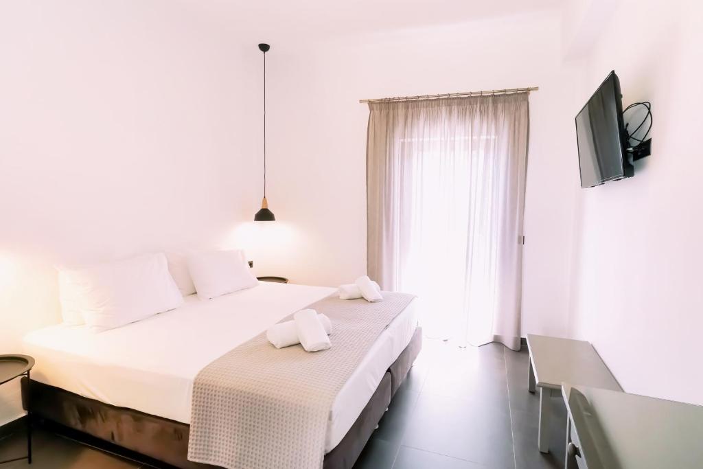 a white bedroom with two beds and a tv at Lefka Ori - Agia Galini in Agia Galini