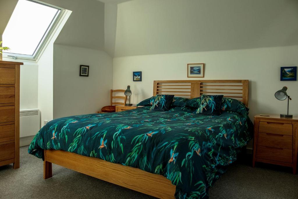 a bedroom with a bed with a green comforter at The Walk-up in Portree