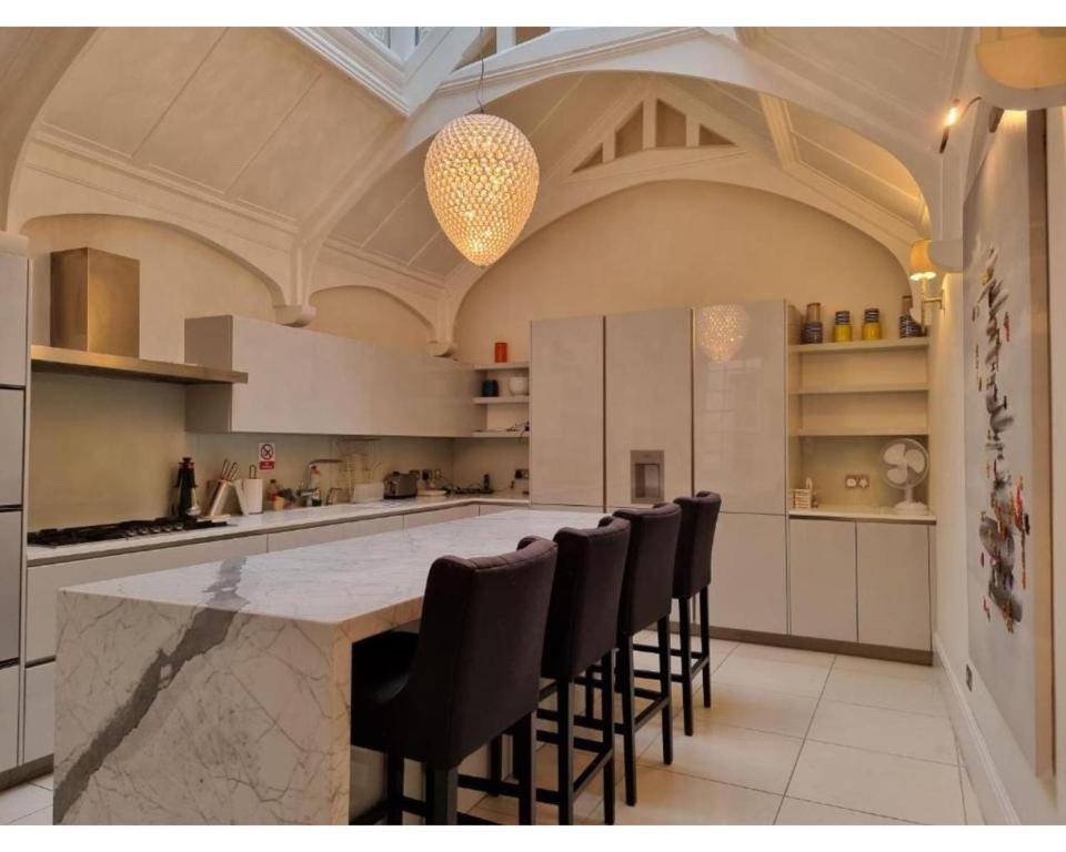 a large kitchen with a large island with black chairs at Victoria Square in London