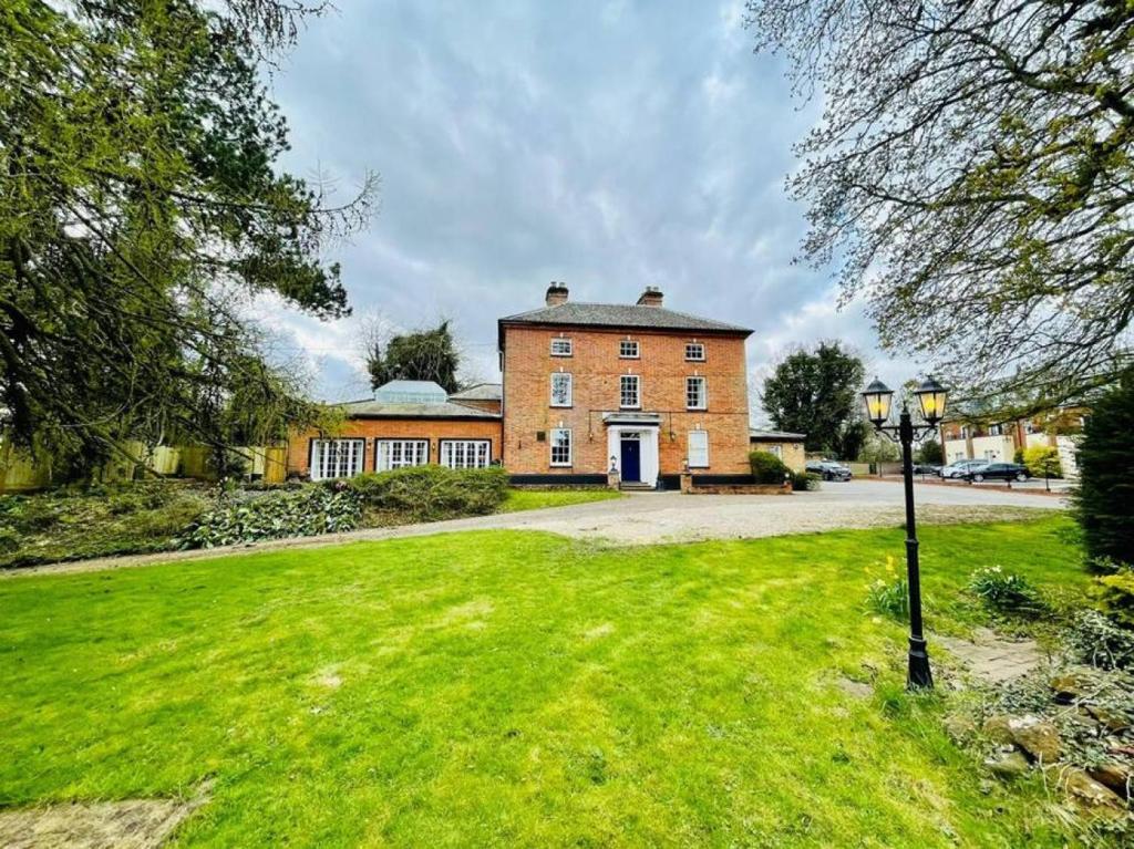 a large brick building with a grass field in front of it at Lydney House Swaffham Sleeps 22 in Swaffham