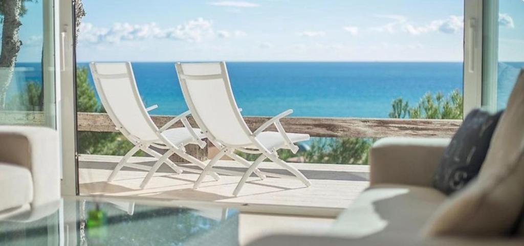 twee witte stoelen op een balkon met uitzicht op de oceaan bij Oliver House in Tarragona