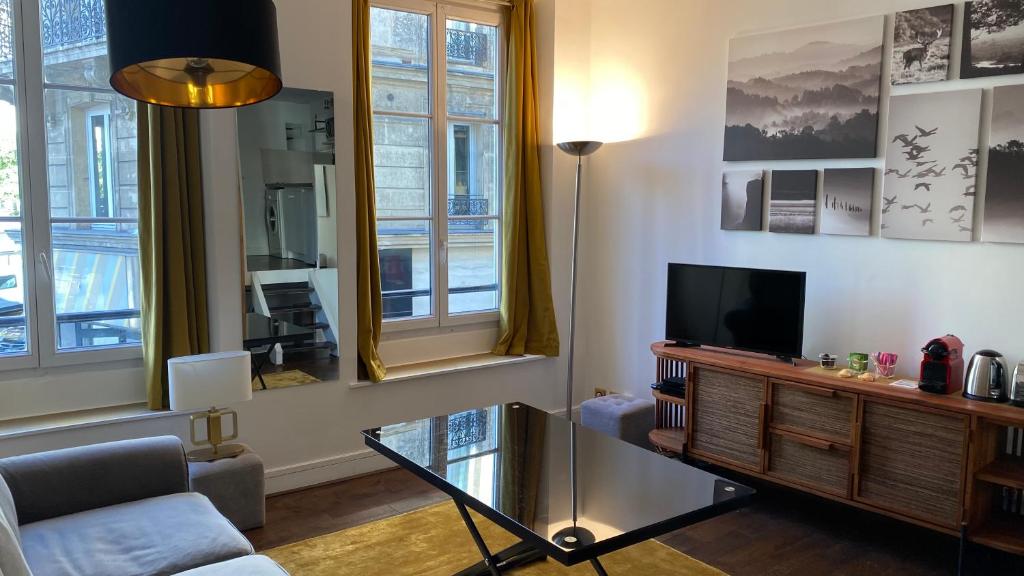- un salon avec une télévision et un canapé dans l'établissement Marais joli deux pièces, à Paris