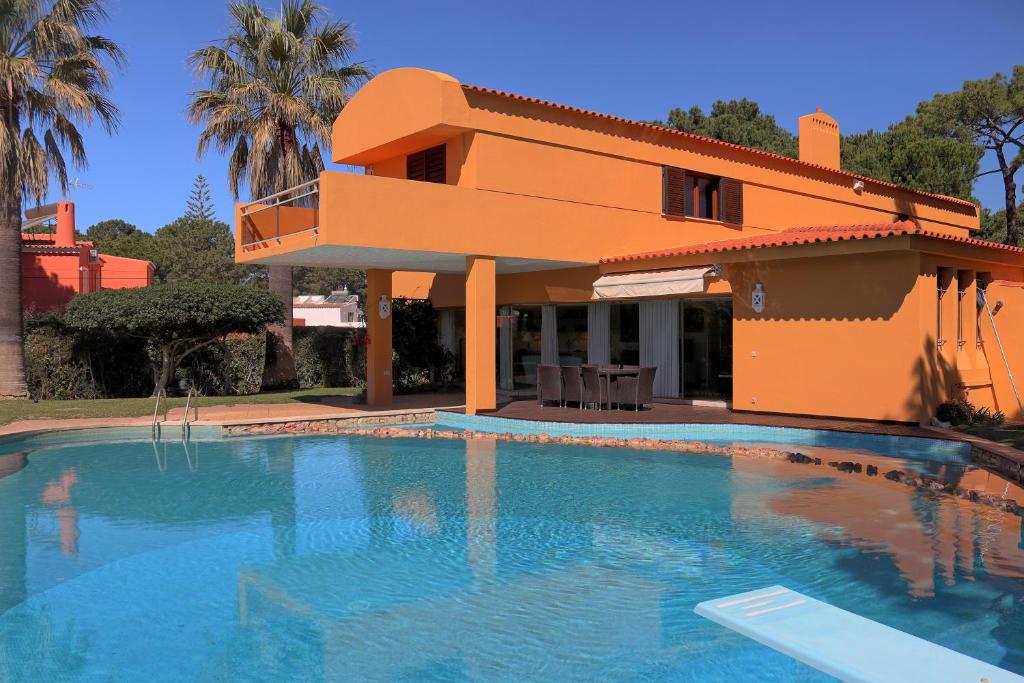 a villa with a swimming pool in front of a house at Casa da Palmeira, pool & soccer pitch in Vilamoura