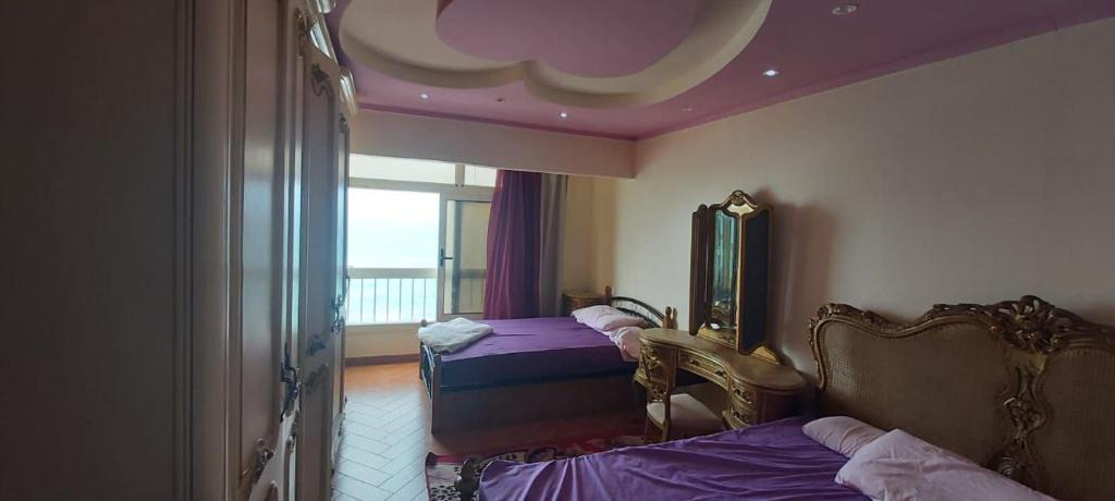 een slaapkamer met 2 bedden, een spiegel en een raam bij ستانلي اسكندريه in Alexandrië