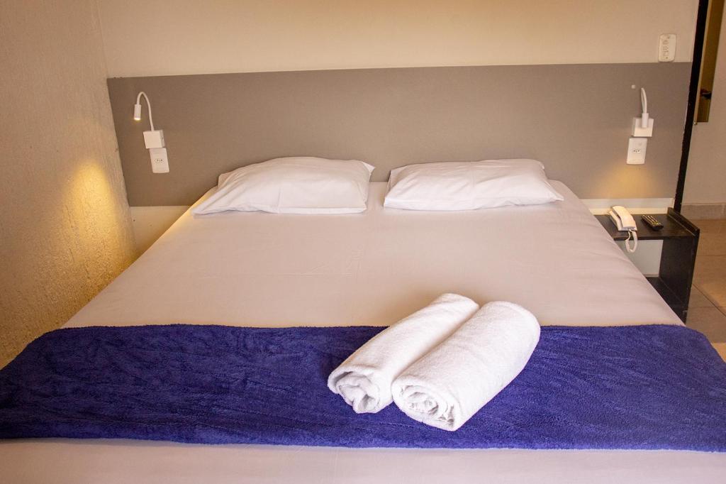 a bed with two rolls of towels on it at Hotel Montana Aeroporto in Brasilia