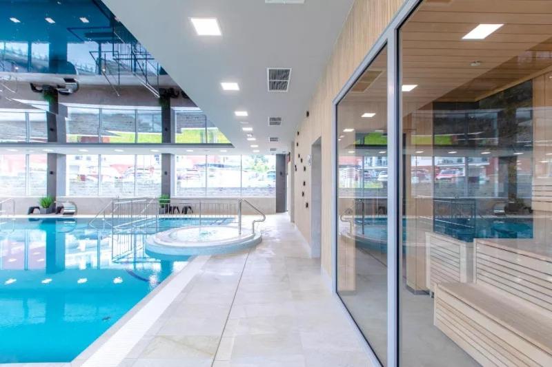 a large swimming pool in a building with glass walls at Apartamenty Klifowa Rewal - Strefa Rekreacji in Rewal