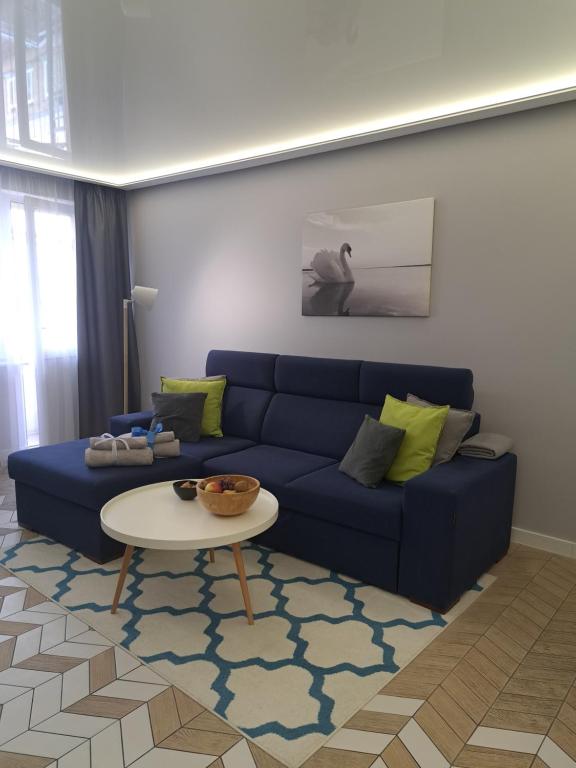 a living room with a blue couch and a table at Apartament Augustów SWAN in Augustów