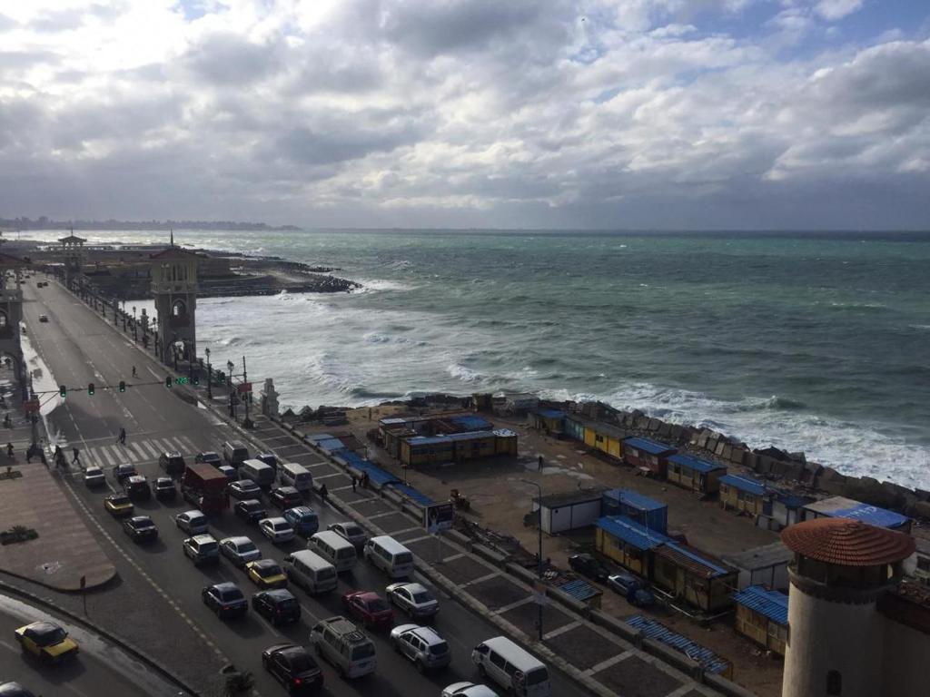 a busy street with cars parked next to the ocean at ستانلي اسكندريه in Alexandria