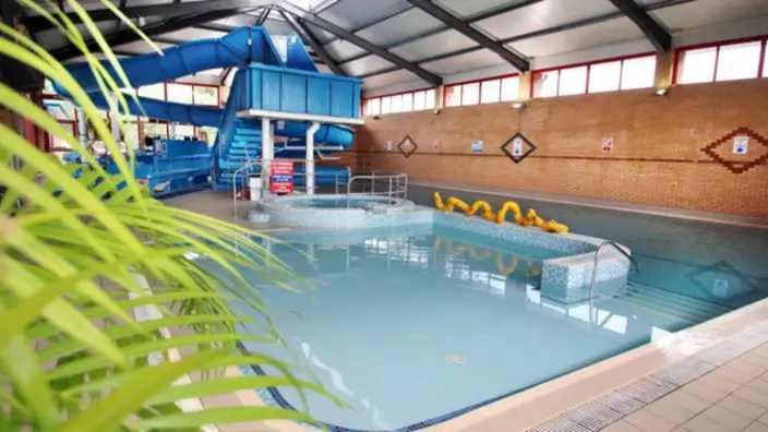 a large indoor swimming pool with a water slide at Oakdene Forest Park Violet 1 in Saint Leonards