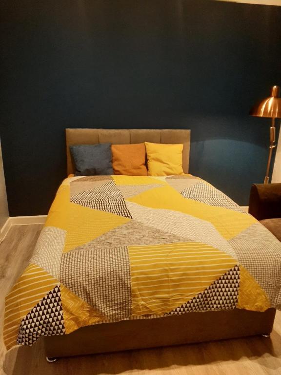 a large bed with a yellow and white comforter at Art Deco Property in Bromley in London