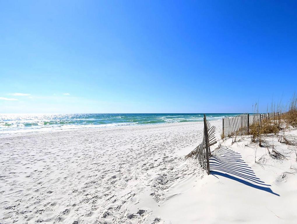 a sandy beach with a fence and the ocean at Villas on the Gulf unit C5 in Pensacola Beach