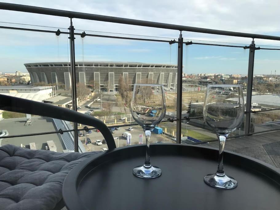 dos copas de vino sentadas en una mesa en un balcón en Aréna Apartman, en Budapest