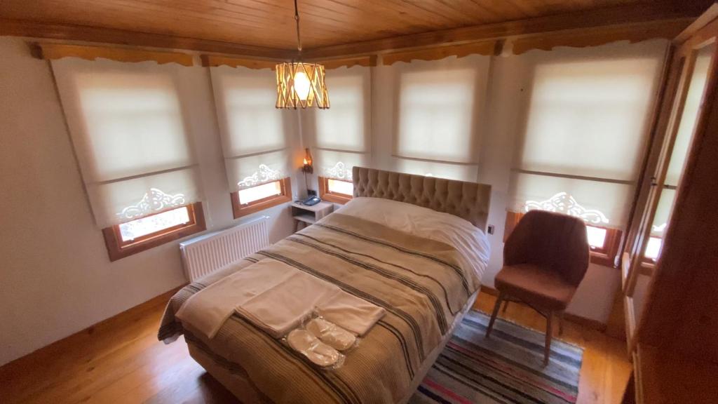 um quarto com uma cama, uma cadeira e janelas em Utku Konağı em Bartın
