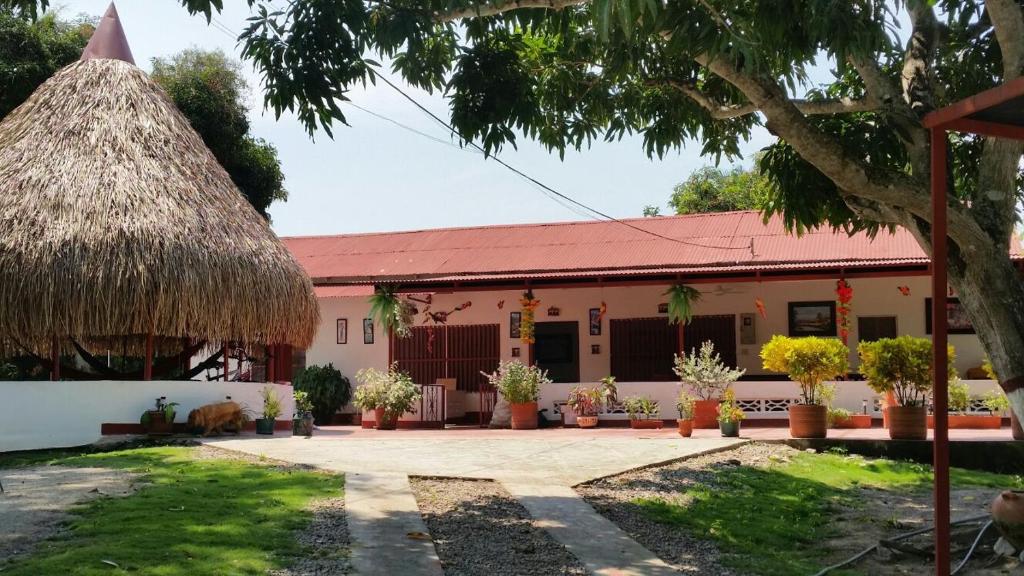 ein Gebäude mit einem Strohdach und einem Hof in der Unterkunft FINCA-CASA DE DESCANSO GUAMO TOLIMA in Guamo