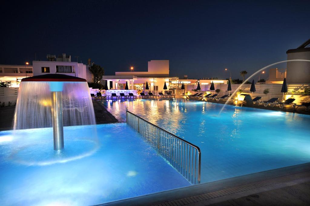 a large swimming pool with a fountain at night at Euronapa Hotel Apartments in Ayia Napa