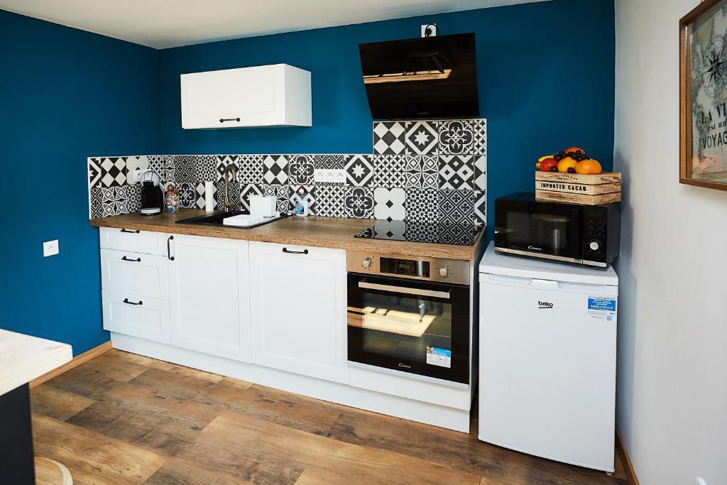 une cuisine avec des placards blancs et un mur bleu dans l'établissement Appartement Ezean belfort ville, à Belfort