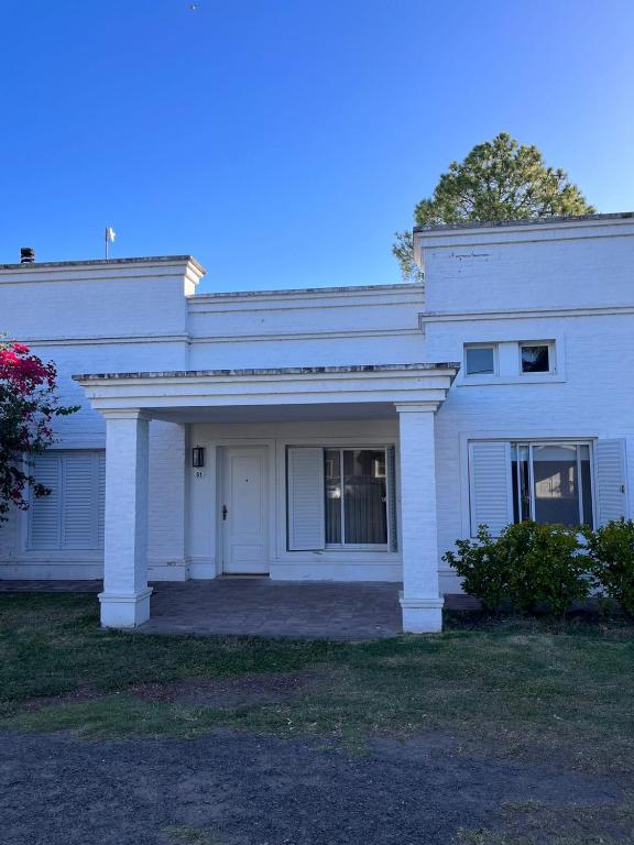 a white house with a porch and a door at Gualeguaychú Golf y verdes in Gualeguaychú