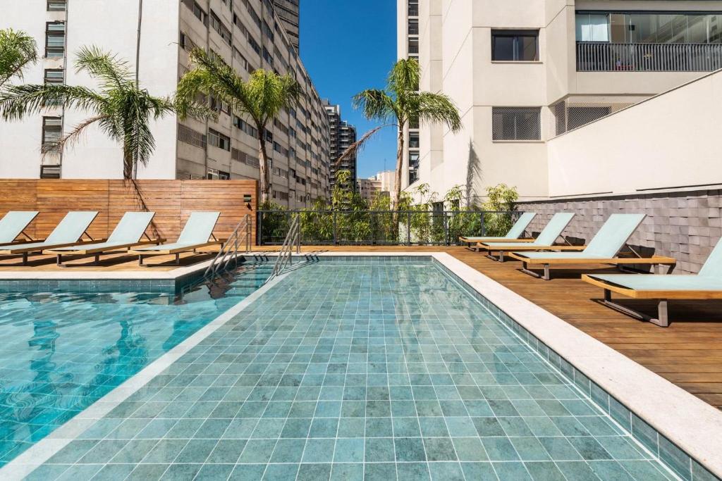 una piscina con tumbonas y un edificio en Kaza Noah Facto Paulista, en São Paulo