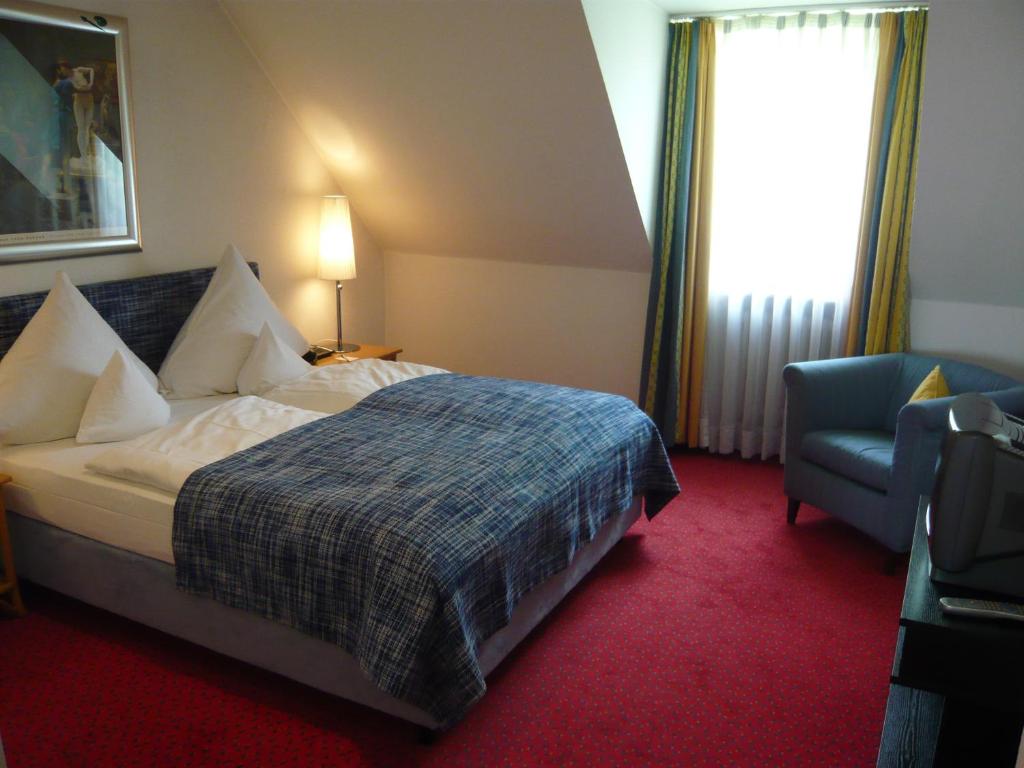 a hotel room with a bed and a chair at Hotel Nymphenburg City - München in Munich