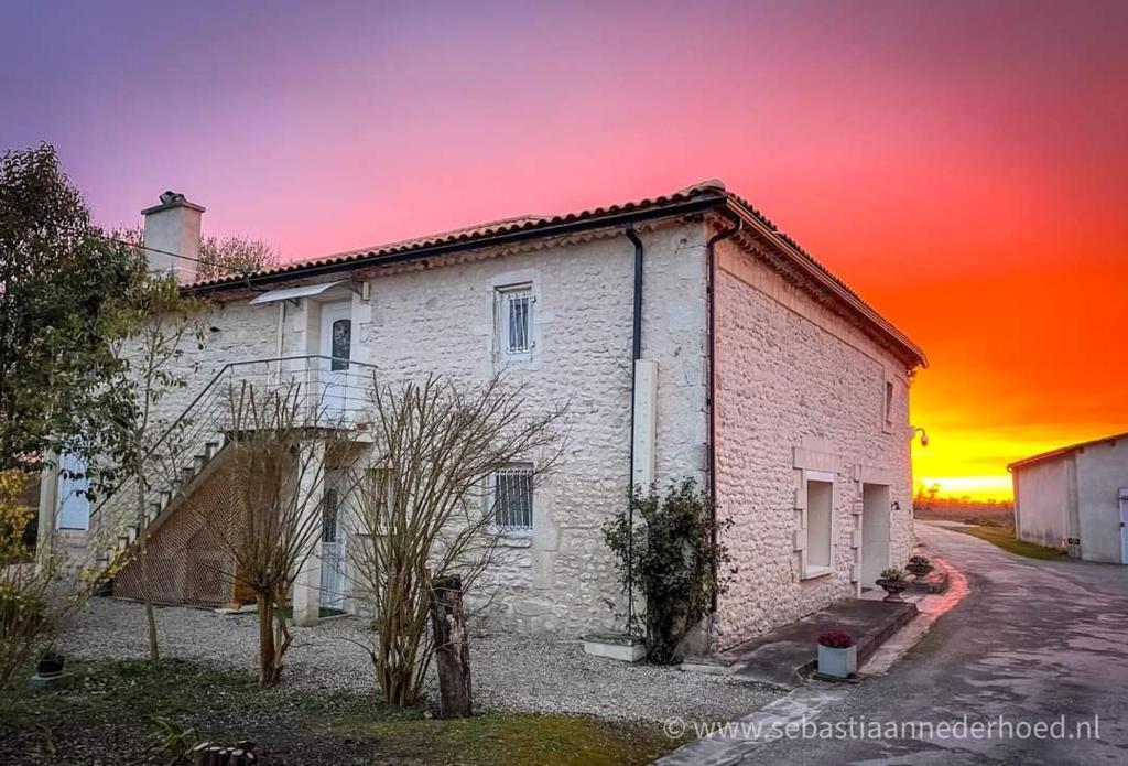 un antiguo edificio de ladrillo blanco con una puesta de sol en el fondo en Chambres d'Hôtes Château Pierre de Montignac, en Civrac-en-Médoc