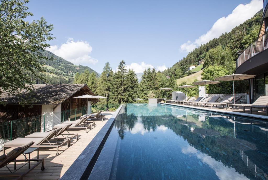 ein Resortpool mit Liegestühlen und einem Berg in der Unterkunft Hotel Bad Fallenbach in St. Leonhard in Passeier