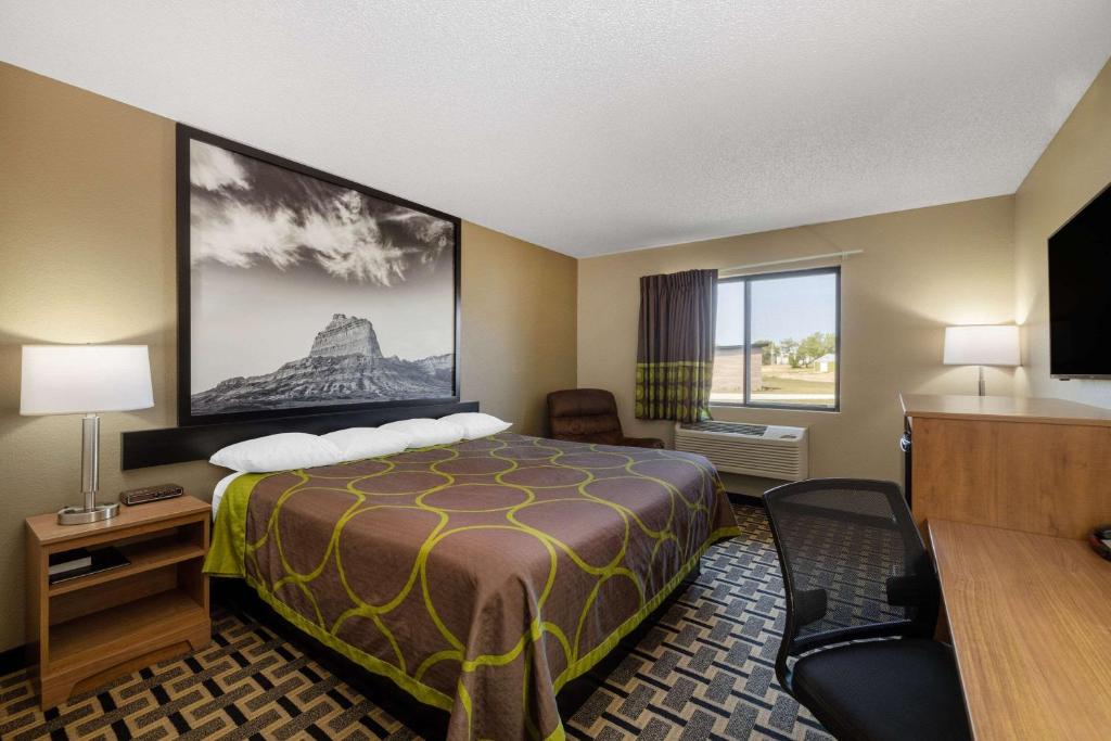 a hotel room with a bed and a desk and a window at Super 8 by Wyndham O Neill NE in O'Neill