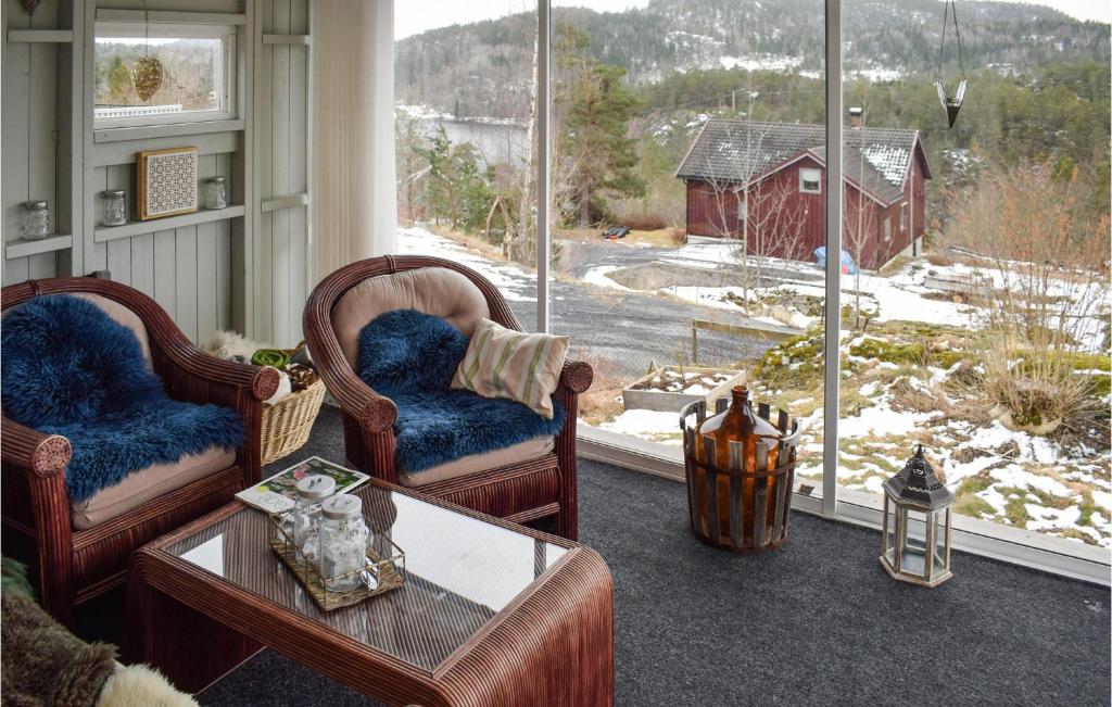 a living room with two chairs and a table and windows at Amazing Home In Krager With Wifi And 3 Bedrooms in Kragerø
