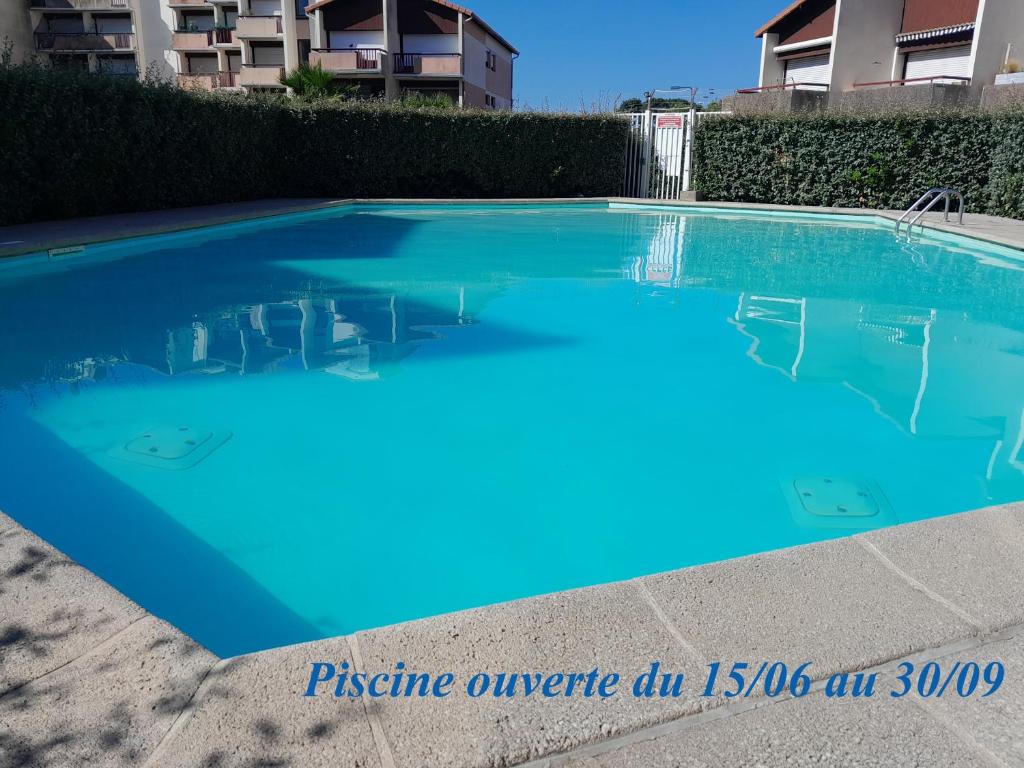 uma piscina azul em frente a um edifício em Joli 2 pièces sur le port avec piscine, terrasse, parking em Capbreton